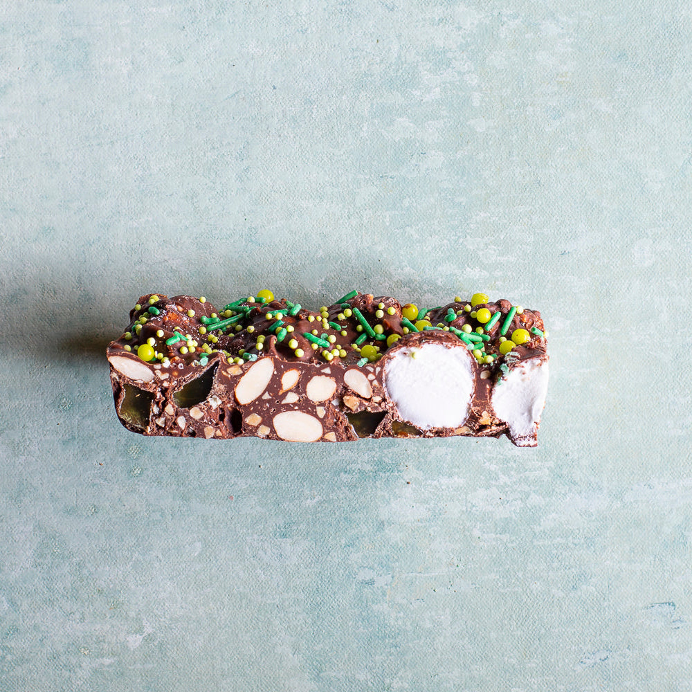 Chocolate bar with nuts and marshmallows and peppermint jellies on a light gray background