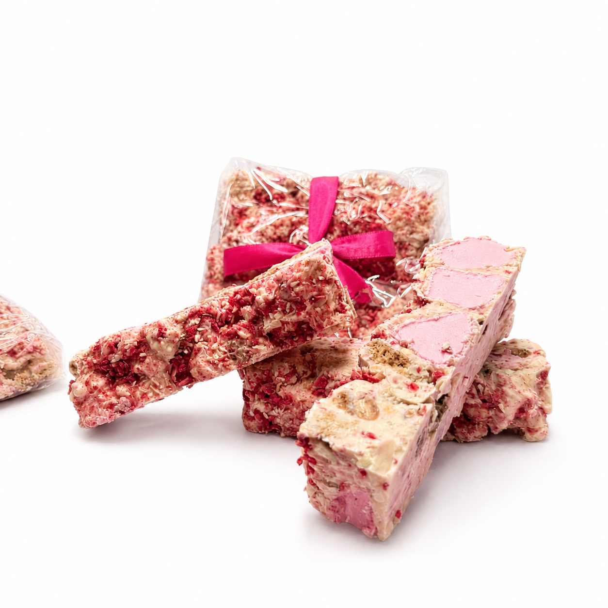 Gift-wrapped Raspberry Roundabout rocky road beside sliced white chocolate rocky road pieces with raspberries and marshmallows.