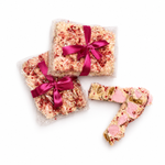 Gift-wrapped Raspberry Roundabout rocky road beside sliced white chocolate rocky road pieces with raspberries and marshmallows.