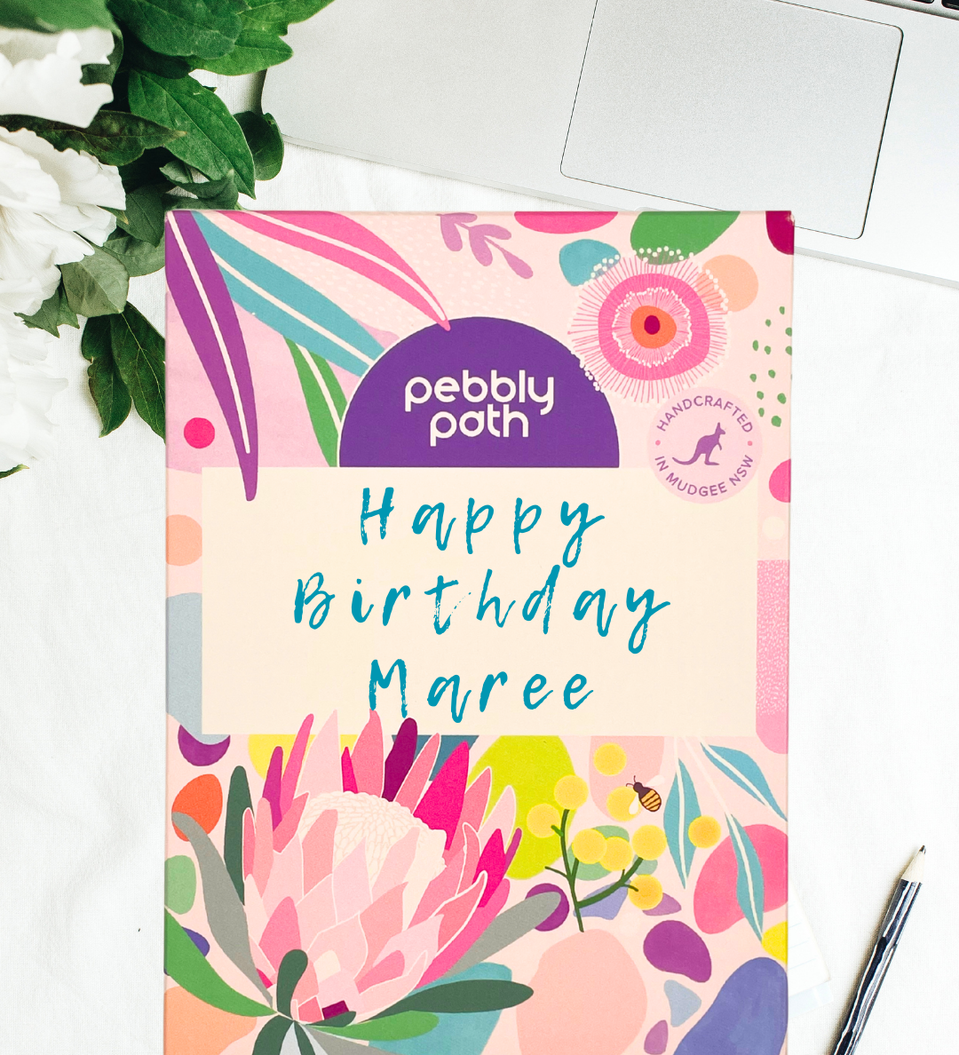 Pebbly Path personalised box of custom rocky road chocolate with handwritten birthday message on floral gift packaging, displayed on a desk beside a laptop and pen.