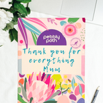 Pebbly Path personalised box of custom rocky road chocolate with a handwritten thank you message for Mum on floral gift packaging, displayed on a desk beside a laptop and pen.