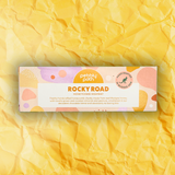 Pebbly Path Honeycomb Highway Rocky Road 100g box displayed on a textured yellow background with branded pastel packaging design.