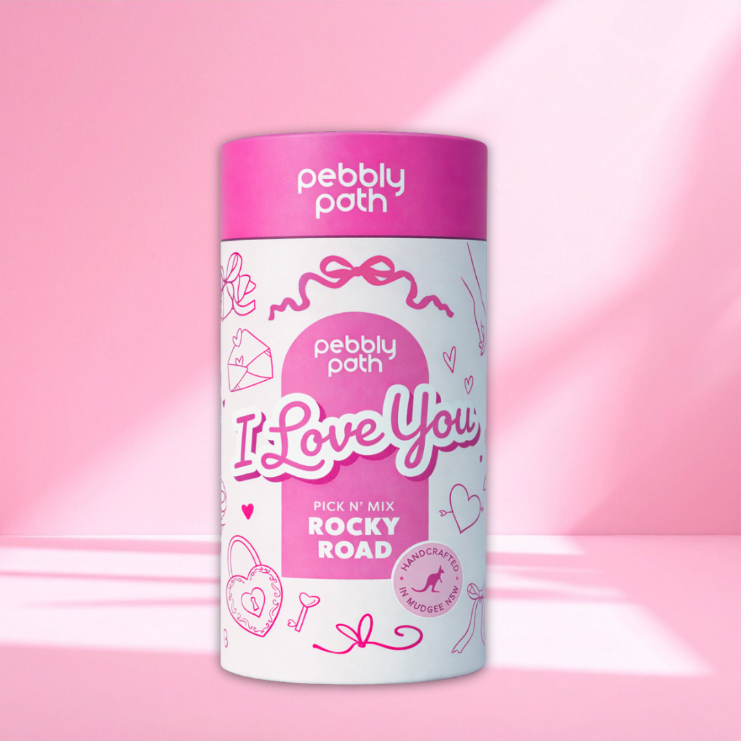 Pebbly Path Pick n Mix “I Love You” rocky road cylinder, a premium Australian handmade chocolate gift in pink and white packaging, styled on a soft pink background.