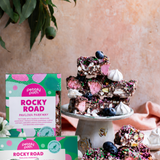 Pebbly Path Pavlova Parkway rocky road in 200g and 100g boxes, displayed with chocolate rocky road pieces topped with blueberries, marshmallows and colourful sprinkles.