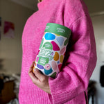 Pebbly Path Pick n Mix Rocky Road Cylinder with a Happy Birthday design, held under one arm by a person wearing a bright pink sweater, highlighting the gift cylinder’s size and colourful packaging.