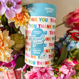 Pebbly Path Pick n Mix Rocky Road Cylinder with a Thank You design, surrounded by colourful flowers in a gift-style arrangement, showcasing a thoughtful appreciation gift for teachers, clients, colleagues, or special occasions.