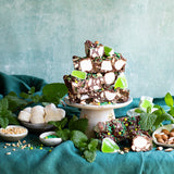 Pebbly Path Mint Motorway Rocky Road slices stacked on a pedestal with fresh mint leaves, marshmallows, almonds and green jelly pieces, presented as a decorative handmade chocolate centrepiece for entertaining or sharing.