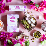 Pebbly Path Turkish Trail Rocky Road grouped 100g and 200g boxes displayed with sliced pieces, nuts, and florals in a styled flat lay for sharing or gifting.
