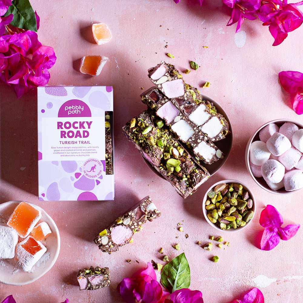 Pebbly Path Turkish Trail Rocky Road 200g box arranged with sliced rocky road and ingredients in a flat lay, presented as a premium chocolate gifting option.