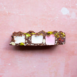 Pebbly Path Turkish Trail Rocky Road close-up slice on a pink textured surface, showing the chocolate texture and ingredients for portion selection and tasting.