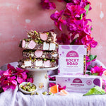 Pebbly Path Turkish Trail Rocky Road slices stacked with grouped 100g and 200g boxes on a styled table, showing the product as a handcrafted chocolate gift.