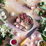 Pebbly Path Pavlova Parkway rocky road pieces arranged on a plate with passionfruit, meringue, pistachios and a knife.