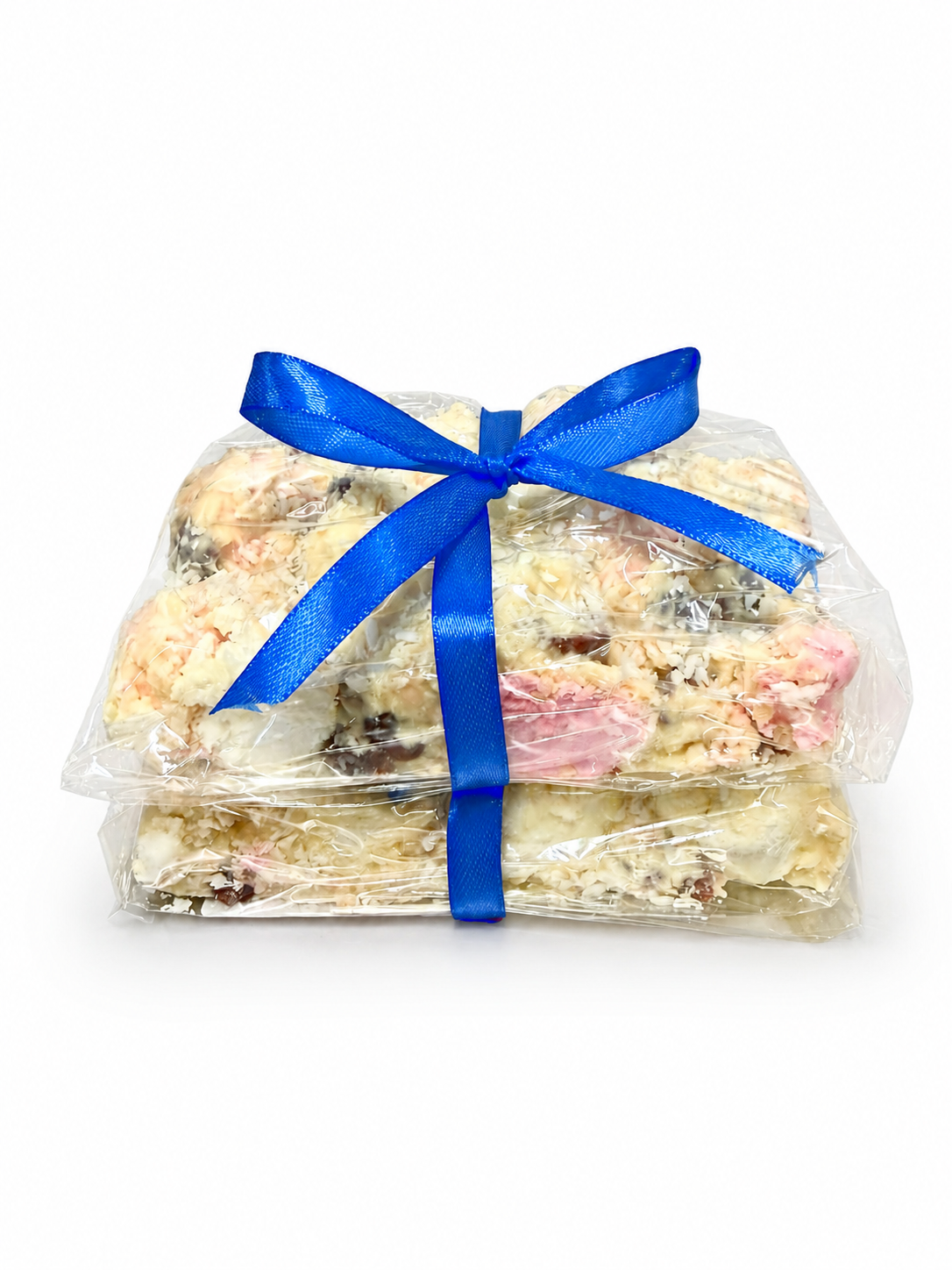 Pebbly Path White Chocolate Signature Recipe Rocky Road stacked pieces wrapped in clear packaging with a blue ribbon, shown from the front with visible coconut flakes, marshmallow, and fruit pieces on a white background.