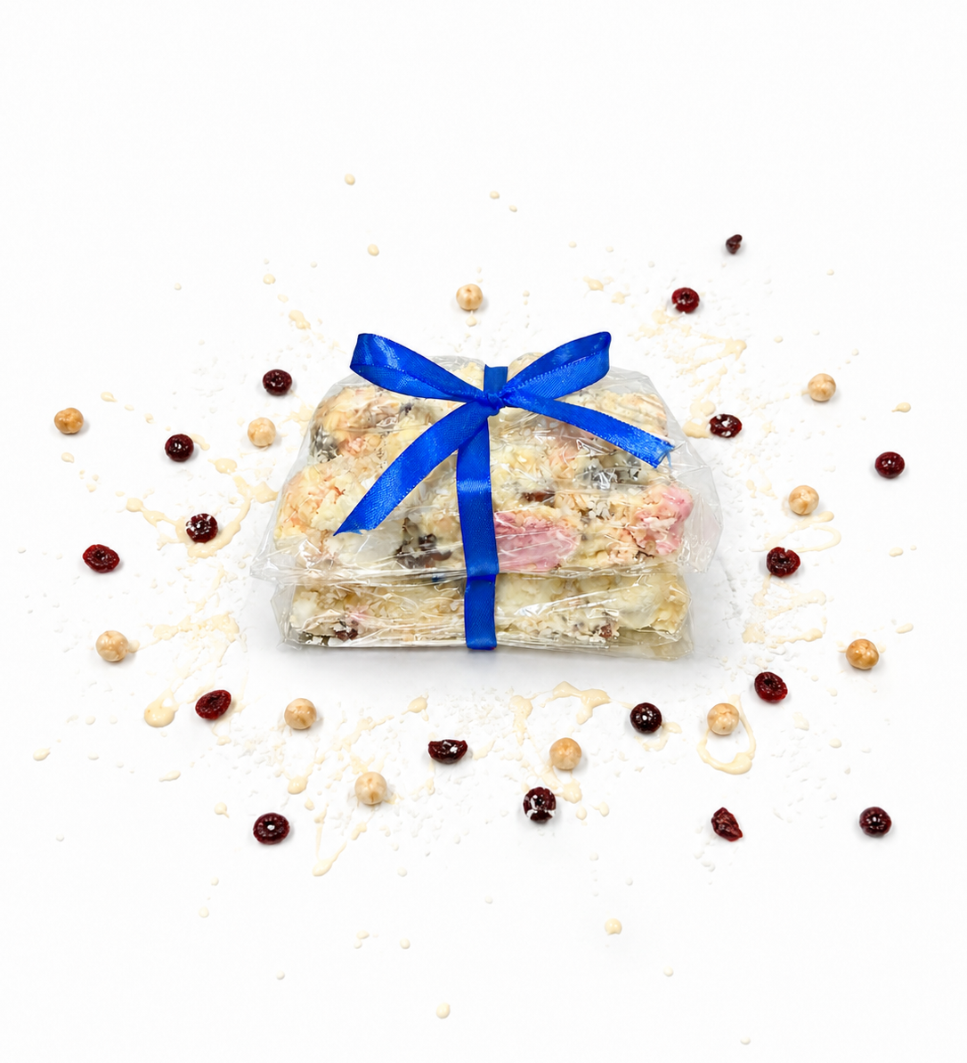 Pebbly Path White Chocolate Signature Recipe Rocky Road stacked pieces wrapped in clear packaging with a blue ribbon, displayed on a white background with coconut flakes, dried cranberries, macadamias, and white chocolate drizzle.