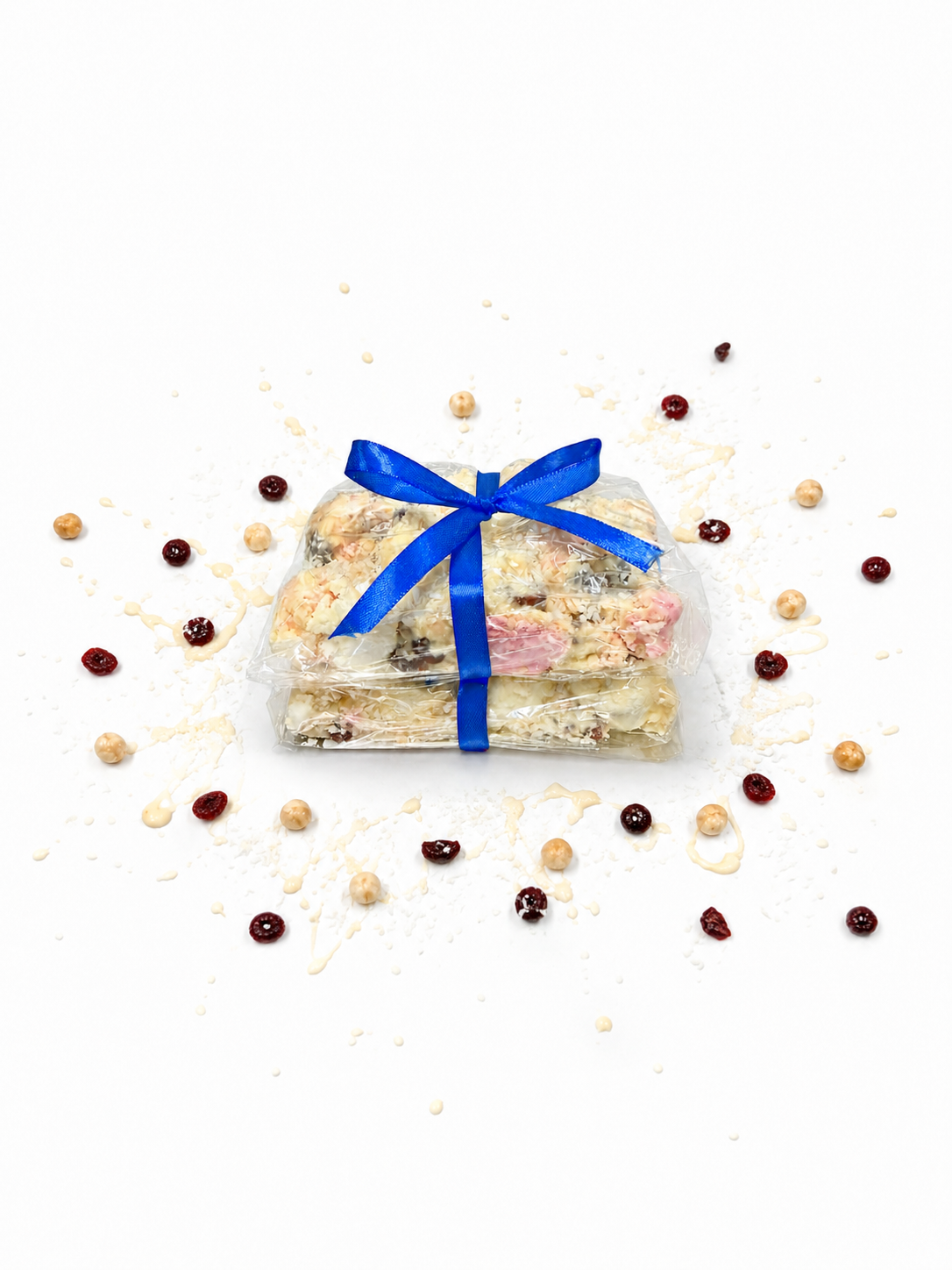 Pebbly Path White Chocolate Signature Recipe Rocky Road stacked pieces wrapped in clear packaging with a blue ribbon, displayed on a white background with coconut flakes, dried cranberries, macadamias, and white chocolate drizzle.