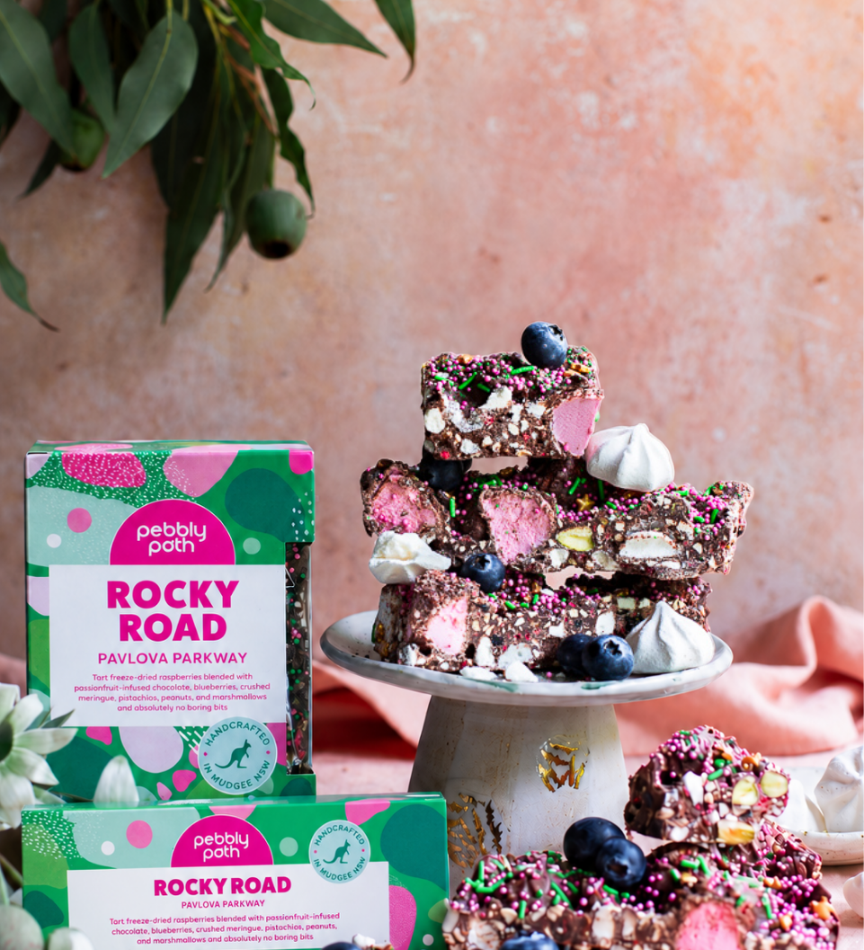 Pebbly Path Pavlova Parkway rocky road 200g and 100g boxes displayed with rocky road pieces, blueberries and meringue.