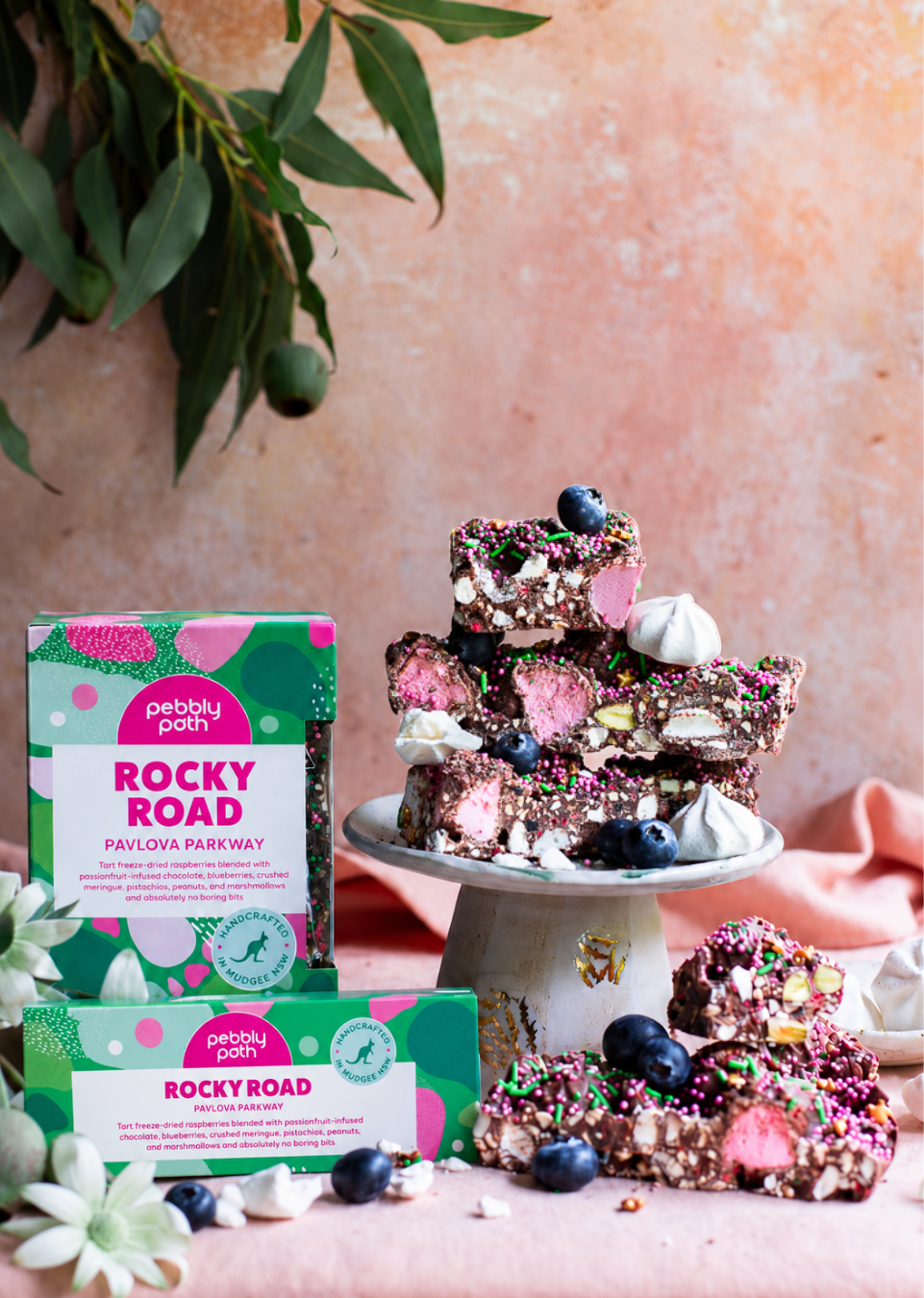 Pebbly Path Pavlova Parkway rocky road 200g and 100g boxes displayed with rocky road pieces, blueberries and meringue.