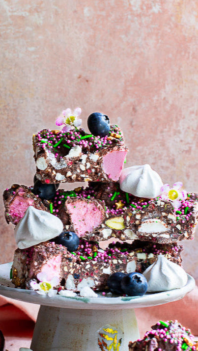 Pebbly Path Pavlova Parkway Rocky Road stacked chocolate pieces with pink marshmallows, blueberries, meringue drops, passionfruit and colourful sprinkles in a styled dessert display