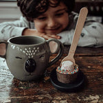 Pebbly Path Hot Chocolate Pop with marshmallow and colourful sprinkles beside a koala mug as a child enjoys a cosy hot chocolate moment at home