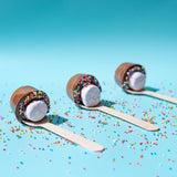 Pebbly Path Hot Chocolate Pops with marshmallows, milk chocolate coating and colourful sprinkles displayed on wooden sticks against a pastel blue background