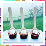 Pebbly Path Hot Chocolate Pops with marshmallows and colourful sprinkles displayed as a trio on a white tray with an outdoor countryside backdrop